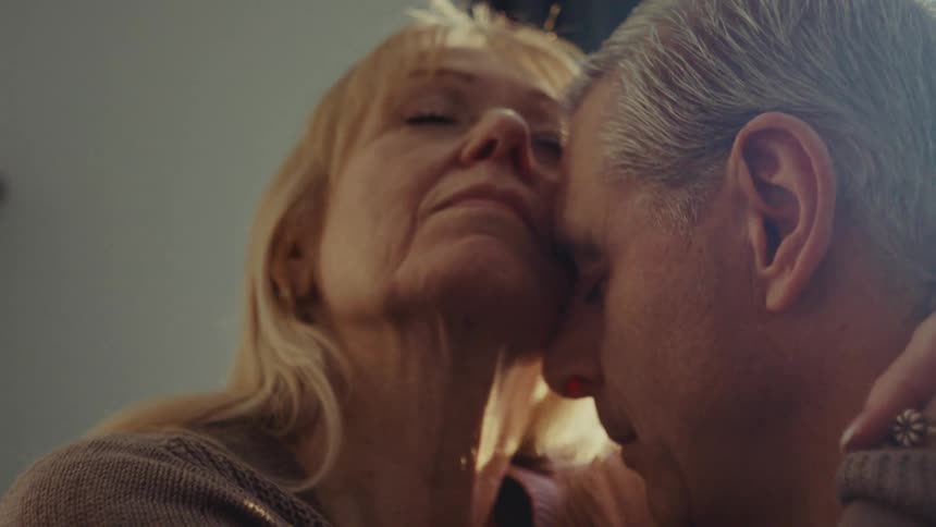 A husband and wife are hugging at home