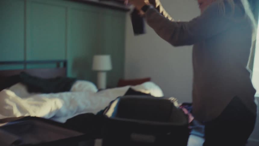 A man and woman are in a hurry packing clothing