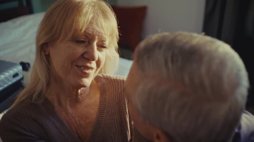 A mature couple shares an intimate and tender moment as a woman with long blonde hair gently embraces an older man with short gray hair