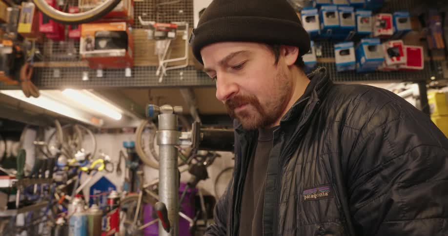 A man in the bike shop is scrolling on his phone