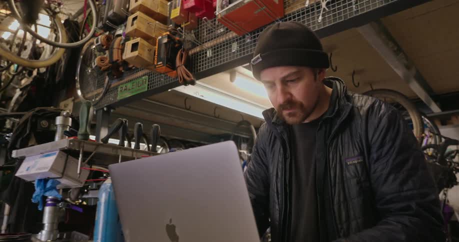 The worker is using a laptop in the bike shop