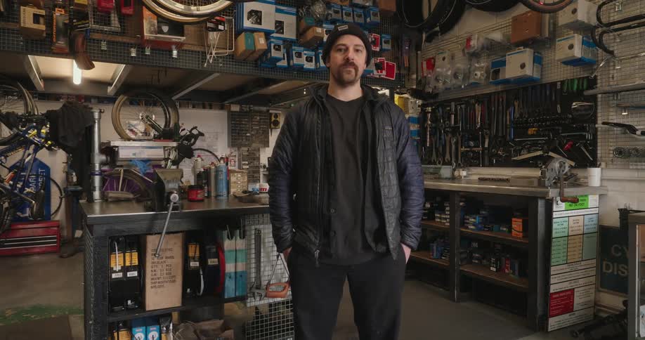 Man in cap inside a shop with bicycle workshop equipment