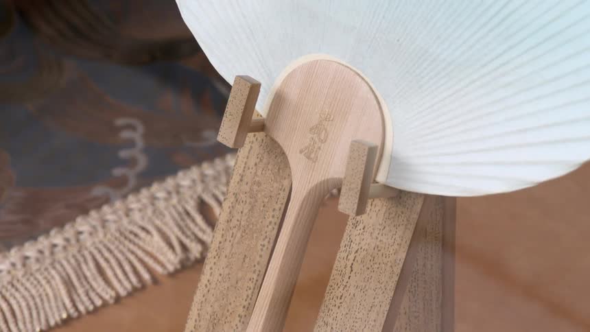 Chinese fan made from paper and wood sits on a wooden display