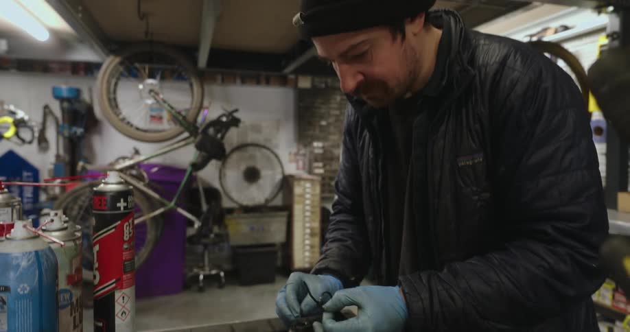 A worker removes a zip tie from a bike part