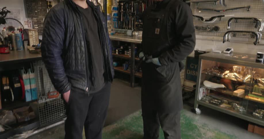 Two men wearing caps standing in a bicycle repair shop