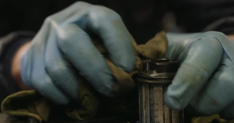 A man is wiping a bike part with a rag