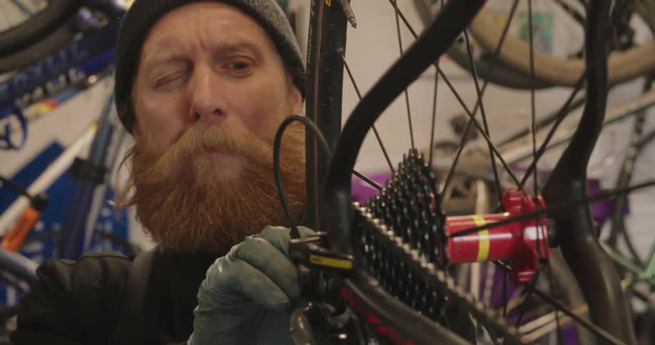 Portrait of a bearded man adjusting a bicycle wheel