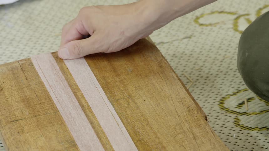 Person gluing a strip of paper to a wooden board