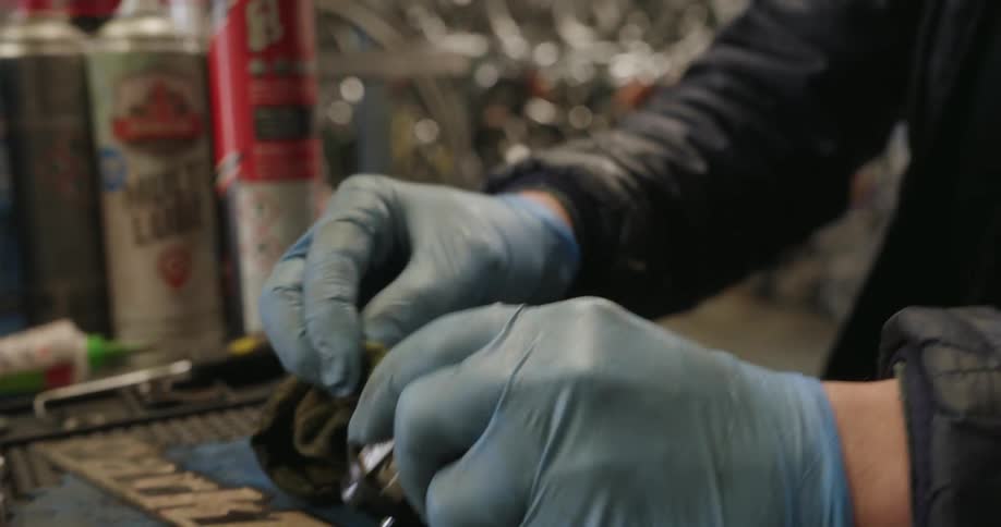 A man cleans a small metal part while working in a bicycle shop