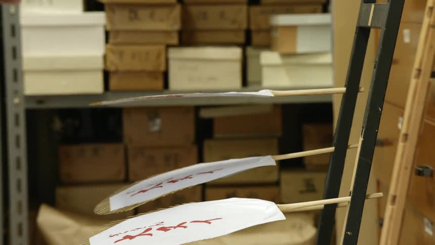 Person hanging paper fans in a rack to dry