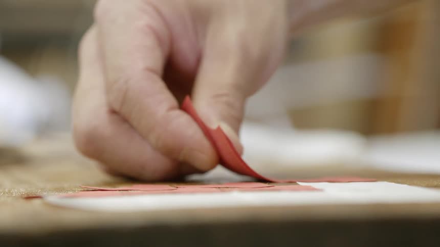 A person places red paper tabs on an object