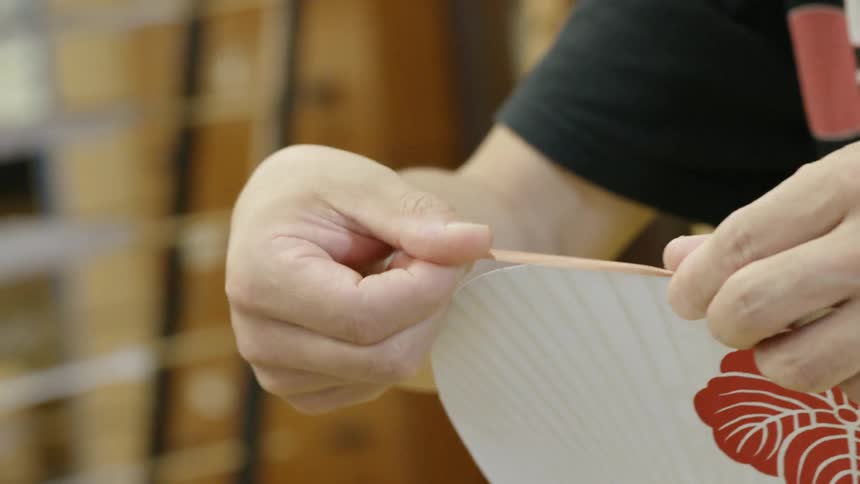 A person applies a border to a white fabric with a flower print
