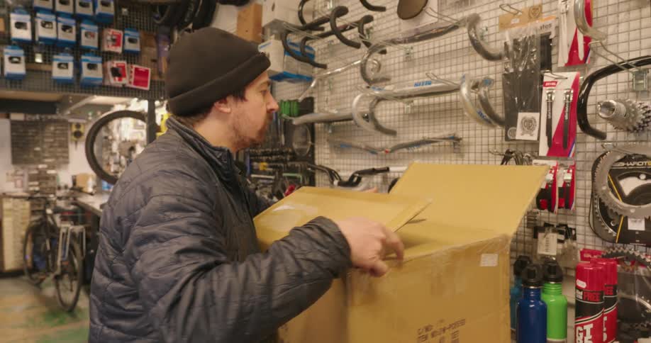 Man in a bike shop packing a box