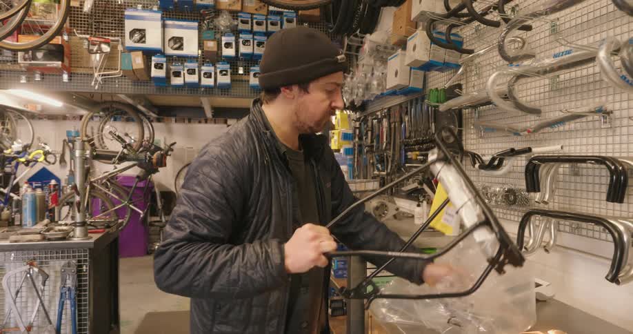 A man is in a bicycle shop unwrapping newparts