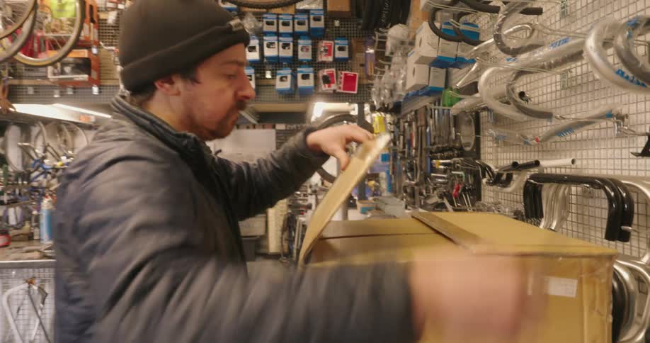 The worker opens up a cardboard box in the store