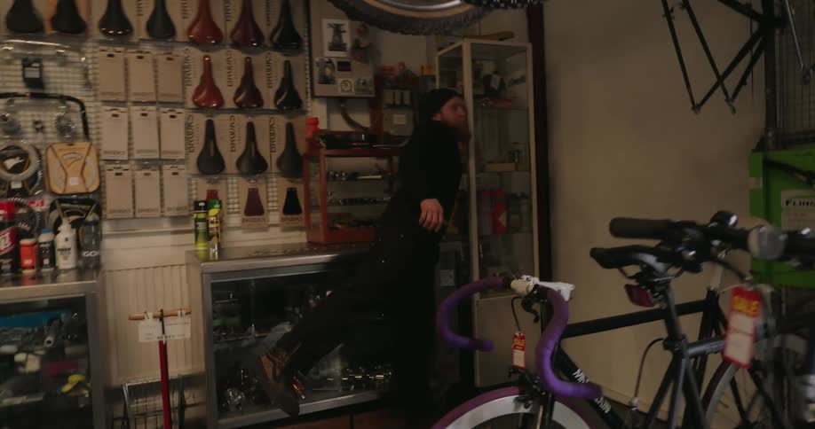A bright bicycle repair shop with tools and bike parts neatly arranged as a person turns on the lights