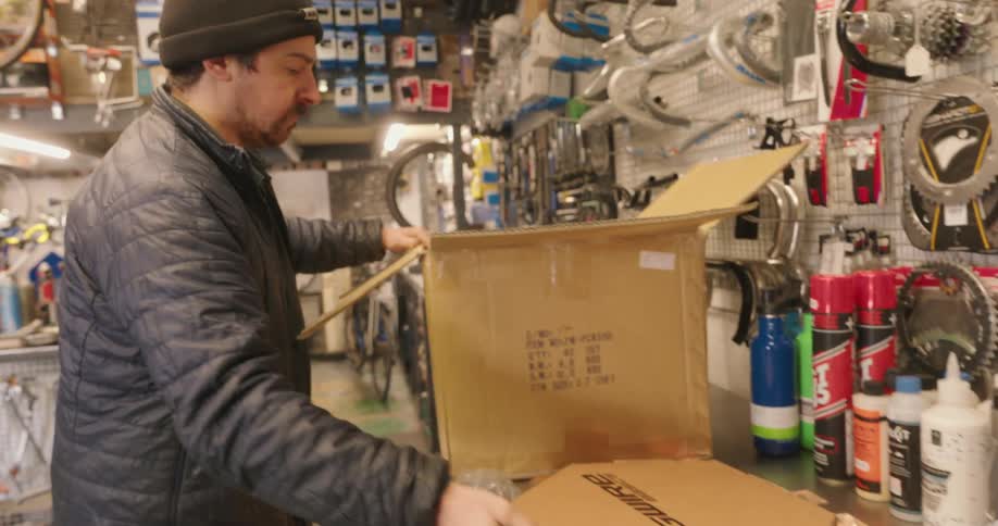 Man working in a bike shop unpacks a package