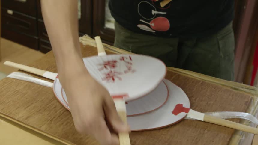 Man arranging paper fans into a pile on a box