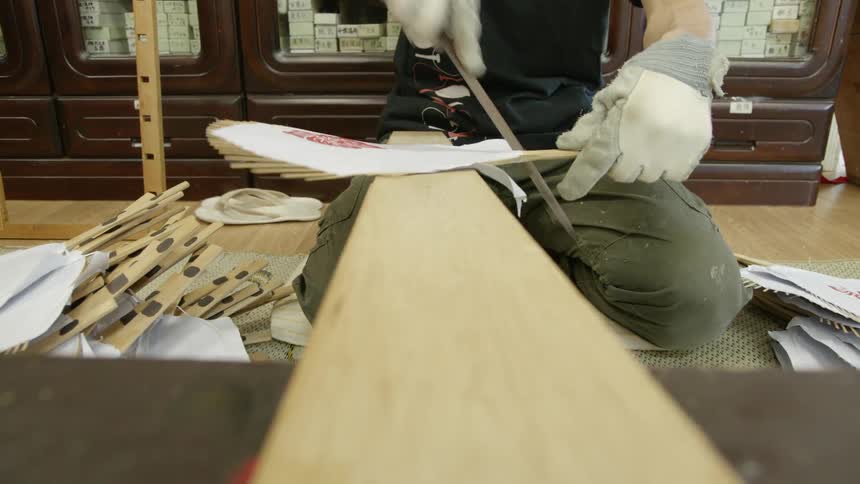 Person filing off scraps from the edge of paper fan