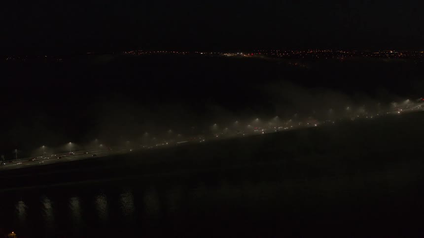 Heavy traffic flows in the fog at night on the bridge