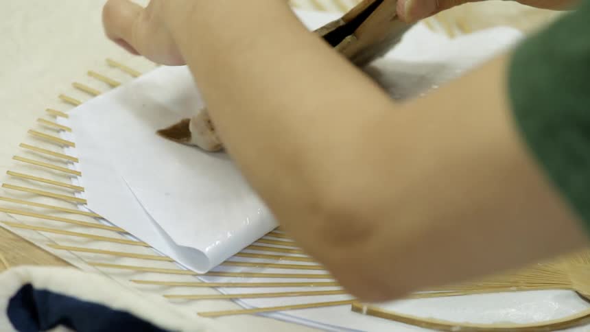 Person brushes paper with glue to make a fan
