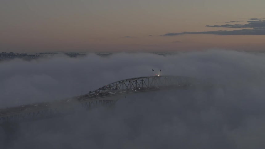 Heavy fog covers the bridge during morning traffic