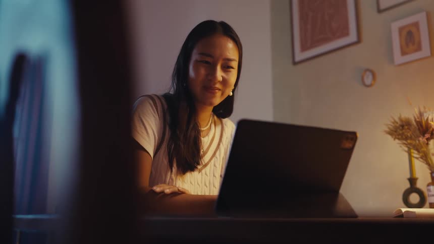 Young woman smiles and waves during a video call on her laptop