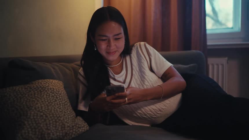 Asian woman with happy facial expression sitting on sofa