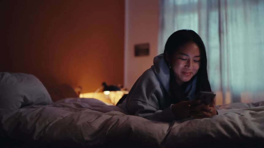 A female is smiling as she texts someone on her phone
