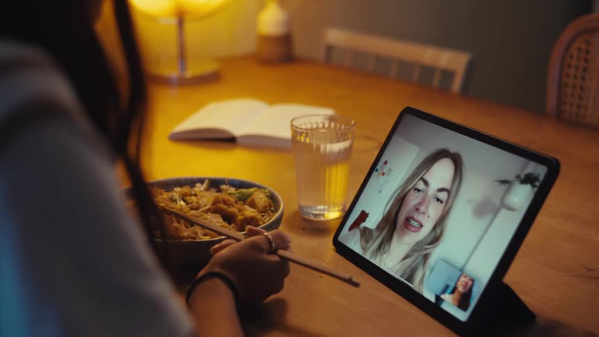Woman talks to a friend via a video call during her mealtime