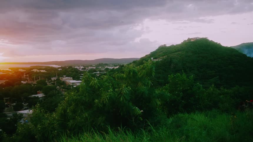 Some people on a high mountain peak at dawn overlooking an urban seaside town