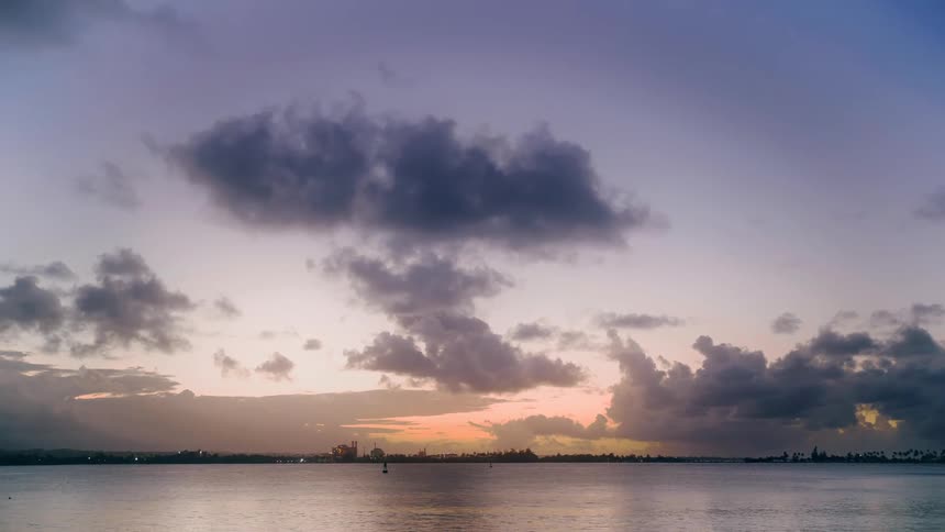 A serene expanse of water reflects a dramatic sky filled with dark textured clouds and a soft glow near the horizon