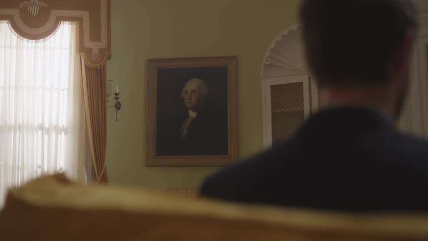 A man leans back in his seat in the oval office