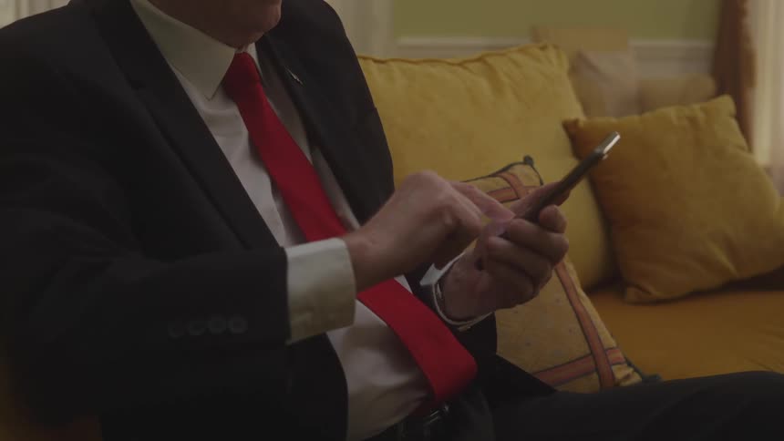 Man in suit sitting interacting with a smartphone