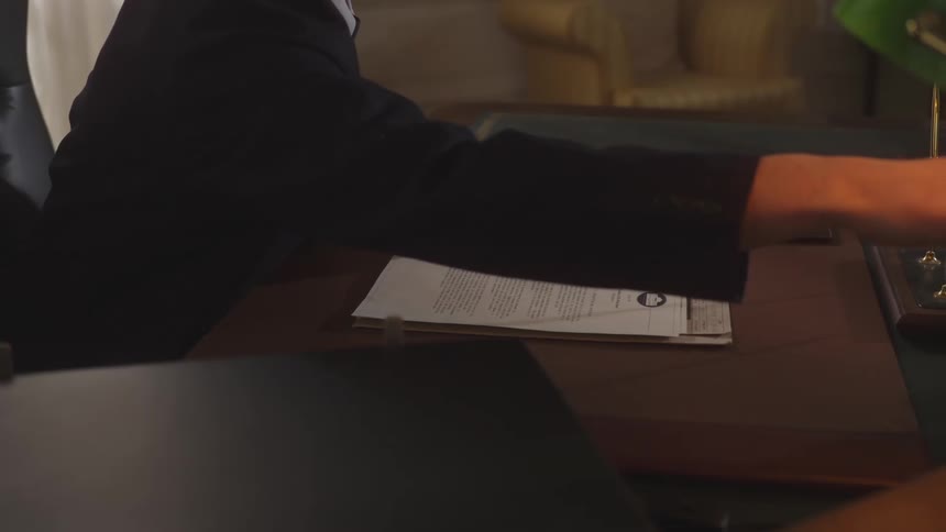 A man lays documents on the desk