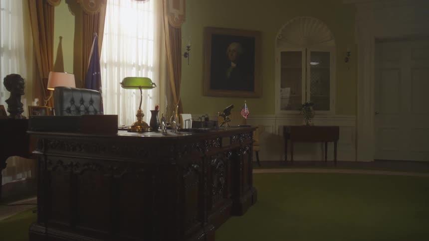 Classic office with carved desk leather chair green lamp and antique portrait on the wall suggesting a government environment