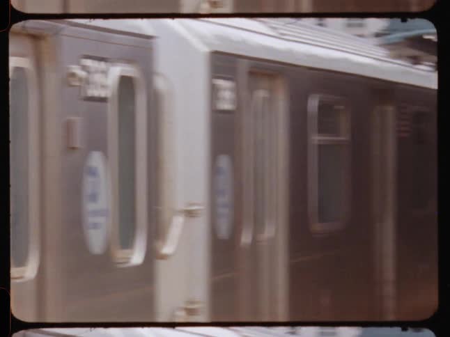 A new york city subway train closes its doors and departs from an outdoor station captured on film