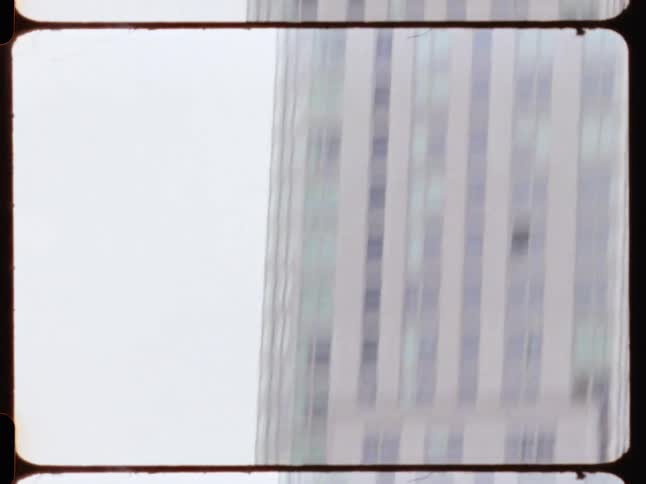 People wait at a train station located next to a skyscraper on a foggy day