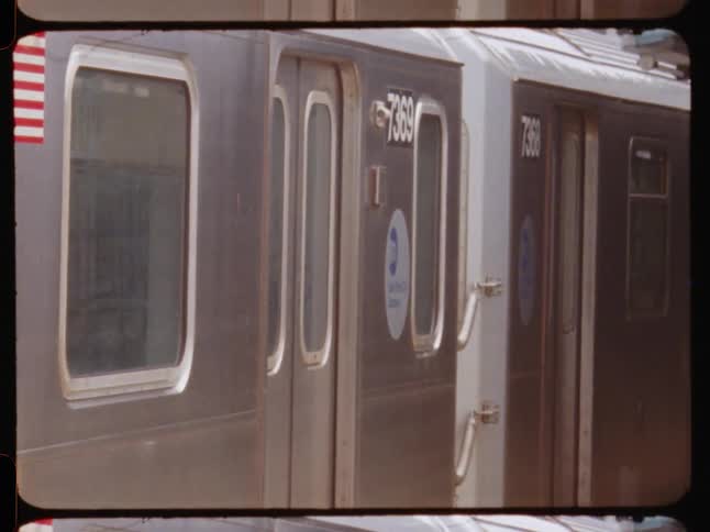 A new york city subway train closes its doors and departs from an outdoor station captured on film
