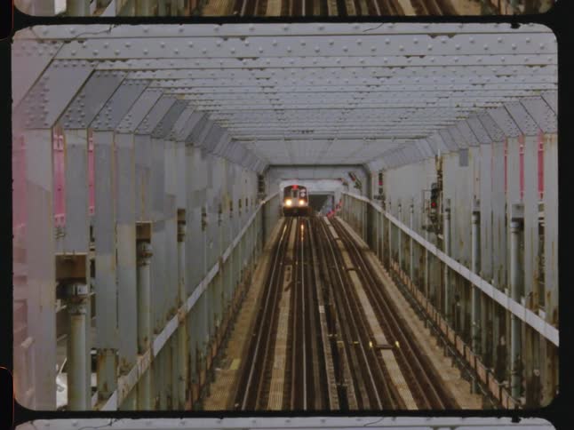 Train travels along the raised tracks paralleling a busy street during the daytime