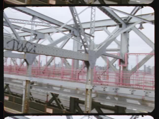 Trains cross over a bridge across the water from the city skyline