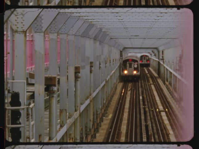 Two trains travel on parallel tracks across a metal bridge