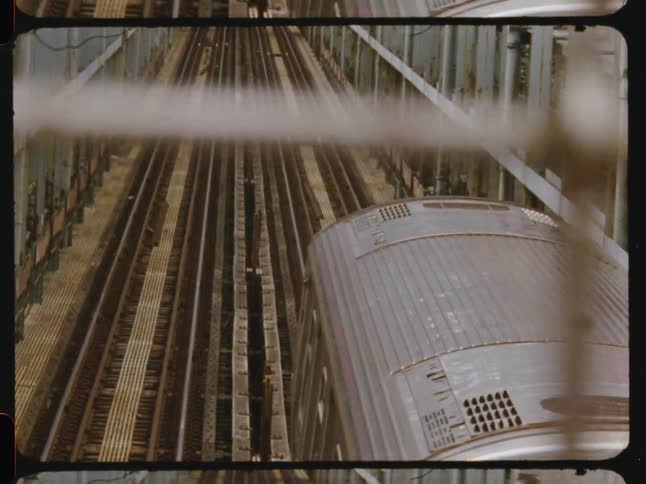 A train traveling on one of multiple rail tracks inside a steel tunnel seen at midday