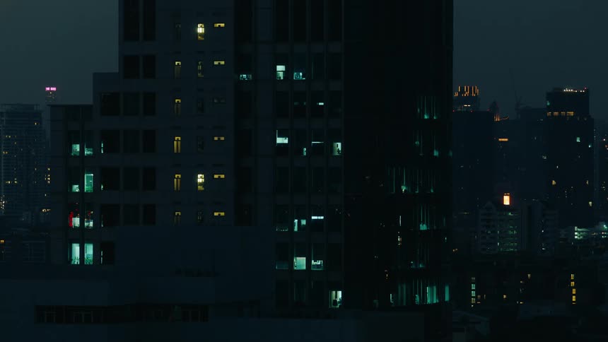 A close up of a tall condominium is shown among other buildings in the city at night