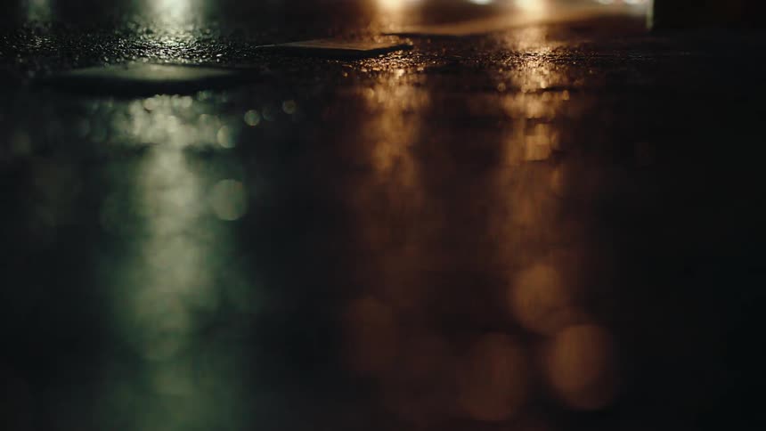 Vehicle lights reflecting on a wet tarred road at night