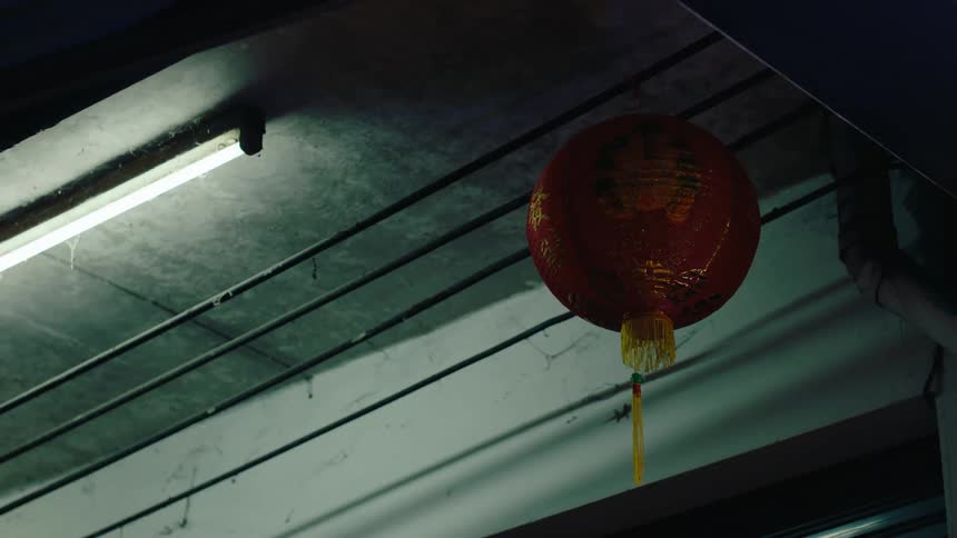 A paper lantern is hanging from the wires at night