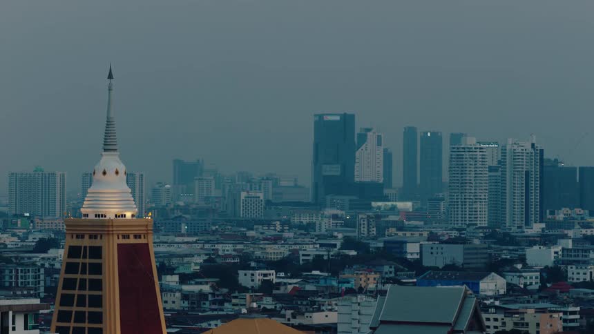 A city skyline featuring an arched tower with a pointed top seen at dawn
