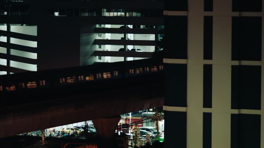 A train runs on a platform between the buildings at night