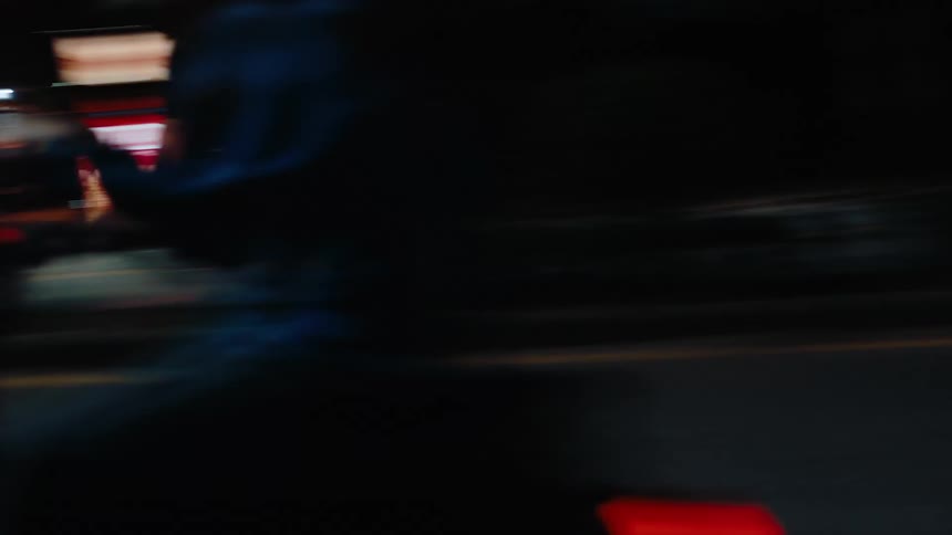 Motorcyclist rides along a city street at night