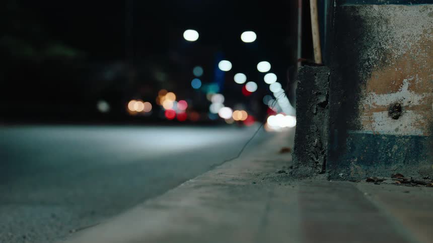 Closeup of the corner of a building while traffic passes the building at night
